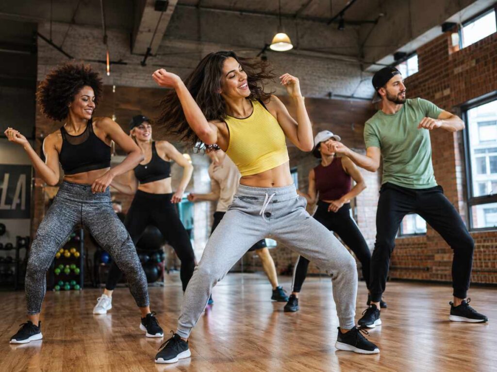 Group of people dancing energetically in a studio fitness class, showing dance as one of the best endurance exercises.