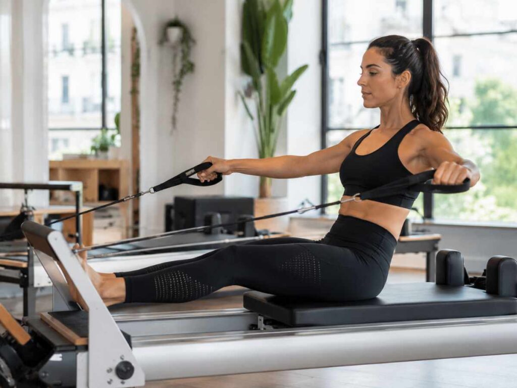 Woman practicing pilates on a reformer machine in a bright studio, one of the best endurance exercises for the core.